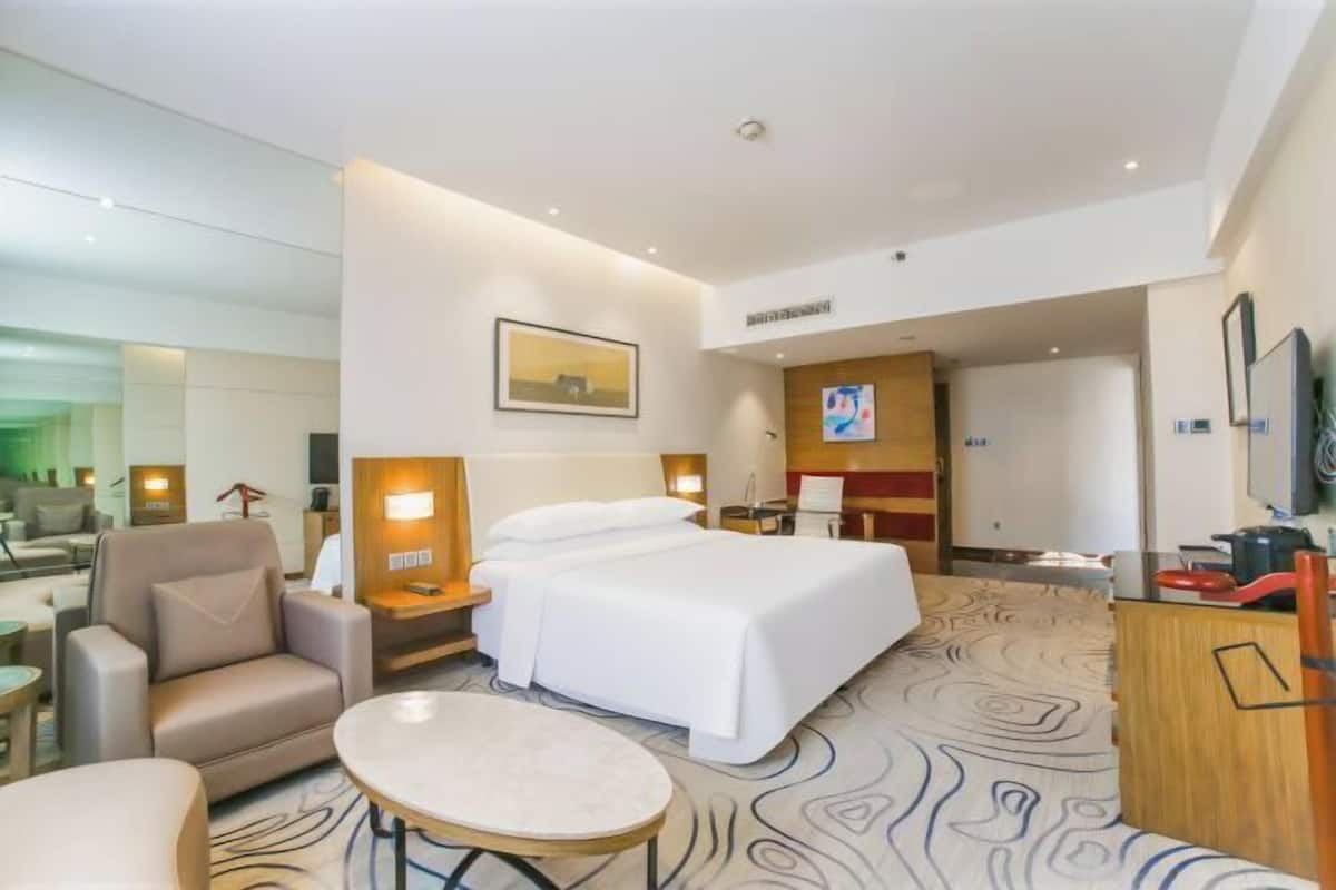 Een hotelkamer met een bed, een bureau, een stoel, een tafeltje en een televisie.