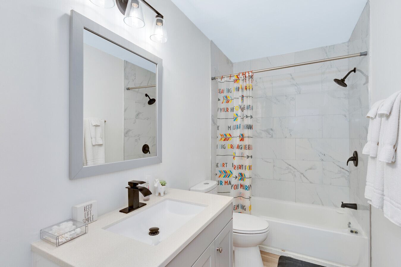 Een moderne badkamer met een grote spiegel, een wastafel, een toilet en een bad.