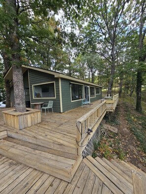 Een chalet met een terras, buitenmeubels en een klein voortuintje.