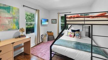 Une chambre avec un lit superposé, un bureau, un globe terrestre et une fenêtre donnant sur des arbres.
