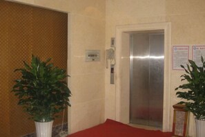 Een lift met een metalen inrichting, een rood tapijt en een aan de muur bevestigd toestel.