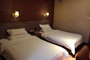 Two single beds with white linens, a wooden headboard, and wall-mounted lamps. - Blue City Exepress Hotel (Chengdu)