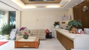 A modern reception area with a sofa, coffee table, and potted plants. - Blue City Exepress Hotel (Chengdu)