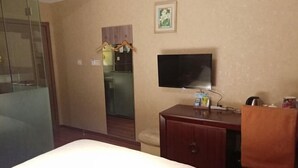 Una habitación de hotel con una cama, un televisor, un armario de madera y un pequeño escritorio.