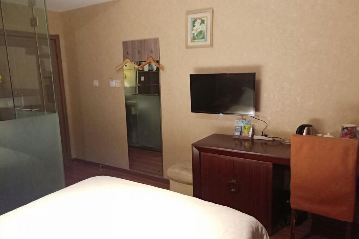 Una habitación de hotel con una cama, un televisor, un armario de madera y un pequeño escritorio.