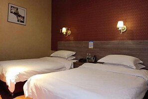 Habitación de hotel con dos camas, cabecero de madera, lámparas de pared e imagen enmarcada.