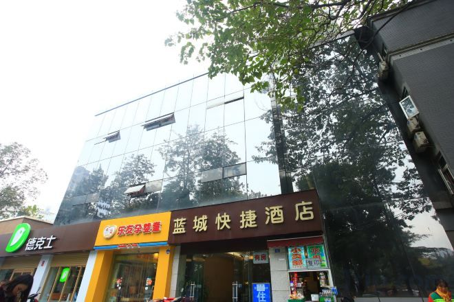 A hotel with a modern glass facade, a visible restaurant sign, and a storefront with a yellow awning.
