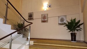 A staircase with a handrail, carpeted steps, and a potted plant on the landing. - Blue City Exepress Hotel (Chengdu)