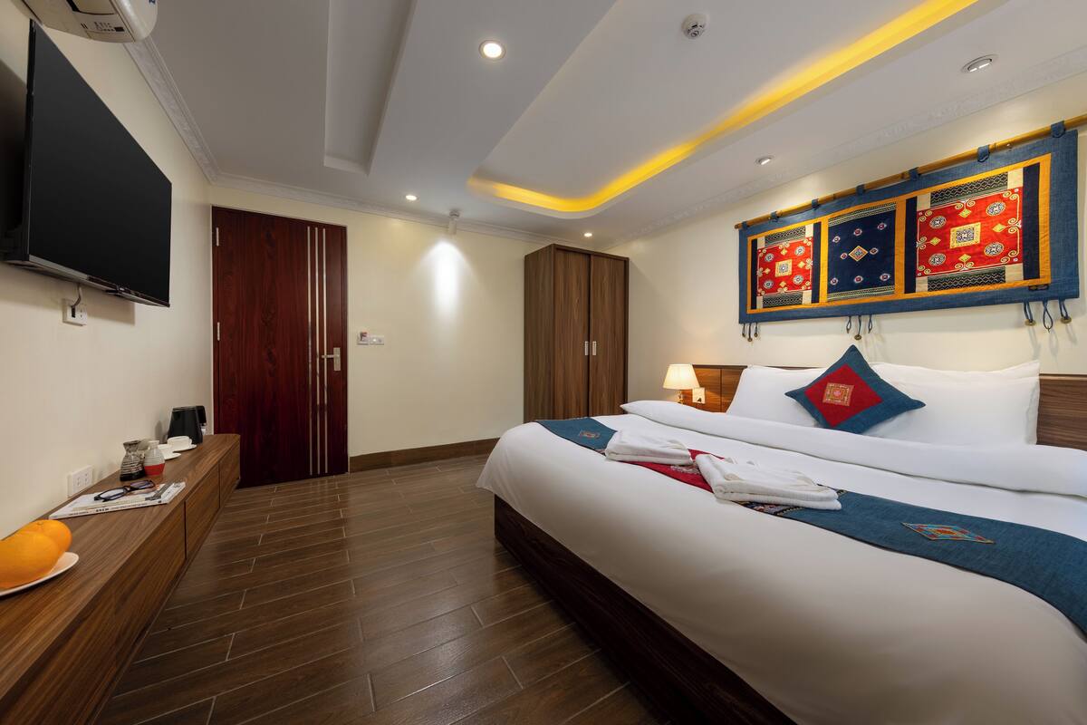 Habitación de hotel con cama, televisor, escritorio y armario.