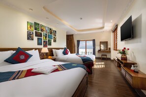Two large beds with neatly arranged pillows and blankets, a flat-screen TV, and a wooden nightstand with a lamp.