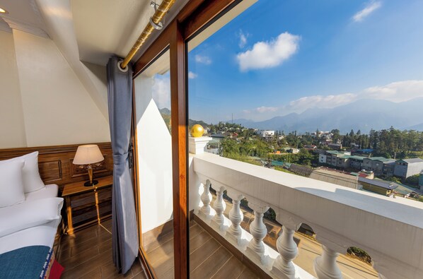 Habitación de hotel con balcón y vistas a la ciudad y montañas.
