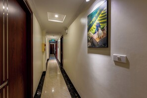 A hotel hallway with a polished marble floor, a wooden door, and a framed picture on the wall. - Sapa TT Homestay (Sa Pa)