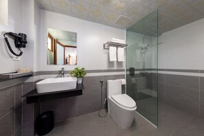 Enjoy a refreshing shower in the sleek bathroom with a glass-enclosed shower, white sink, and toilet.