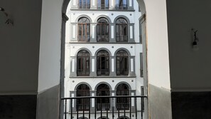 Un edificio de varios pisos con ventanas arqueadas y un balcón con barandilla negra.