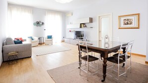 Ein modernes Wohnzimmer mit Esstisch, Stühlen, einer Couch und einem Fernseher.
