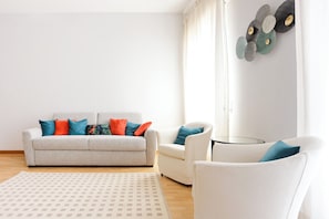 A living room with a sofa, two armchairs, a coffee table, and a patterned rug.