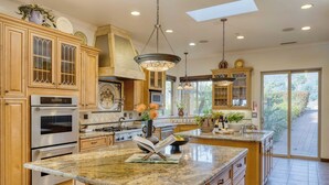 A spacious kitchen with granite countertops, stainless steel appliances, and wooden cabinetry. - Keys Creek Main House by Avantstay Luxury 9bdr Estate (Valley Center)