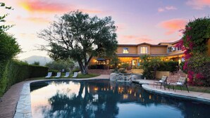 A swimming pool with lounge chairs, a patio area, and a building with a tiled roof. - Keys Creek Main House by Avantstay Luxury 9bdr Estate (Valley Center)