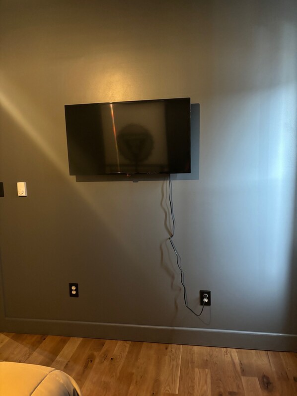 Ein Flachbildfernseher an der Wand befestigt, mit sichtbarem Stromkabel.