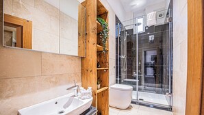 Une salle de bain moderne avec un grand lavabo, des étagères en bois, des toilettes et une douche à parois de verre.