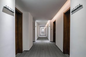 A hotel hallway with doors numbered 60703 and 60706, carpeted flooring, and a modern light fixture. - Bo Man Hotel (Pu'er)