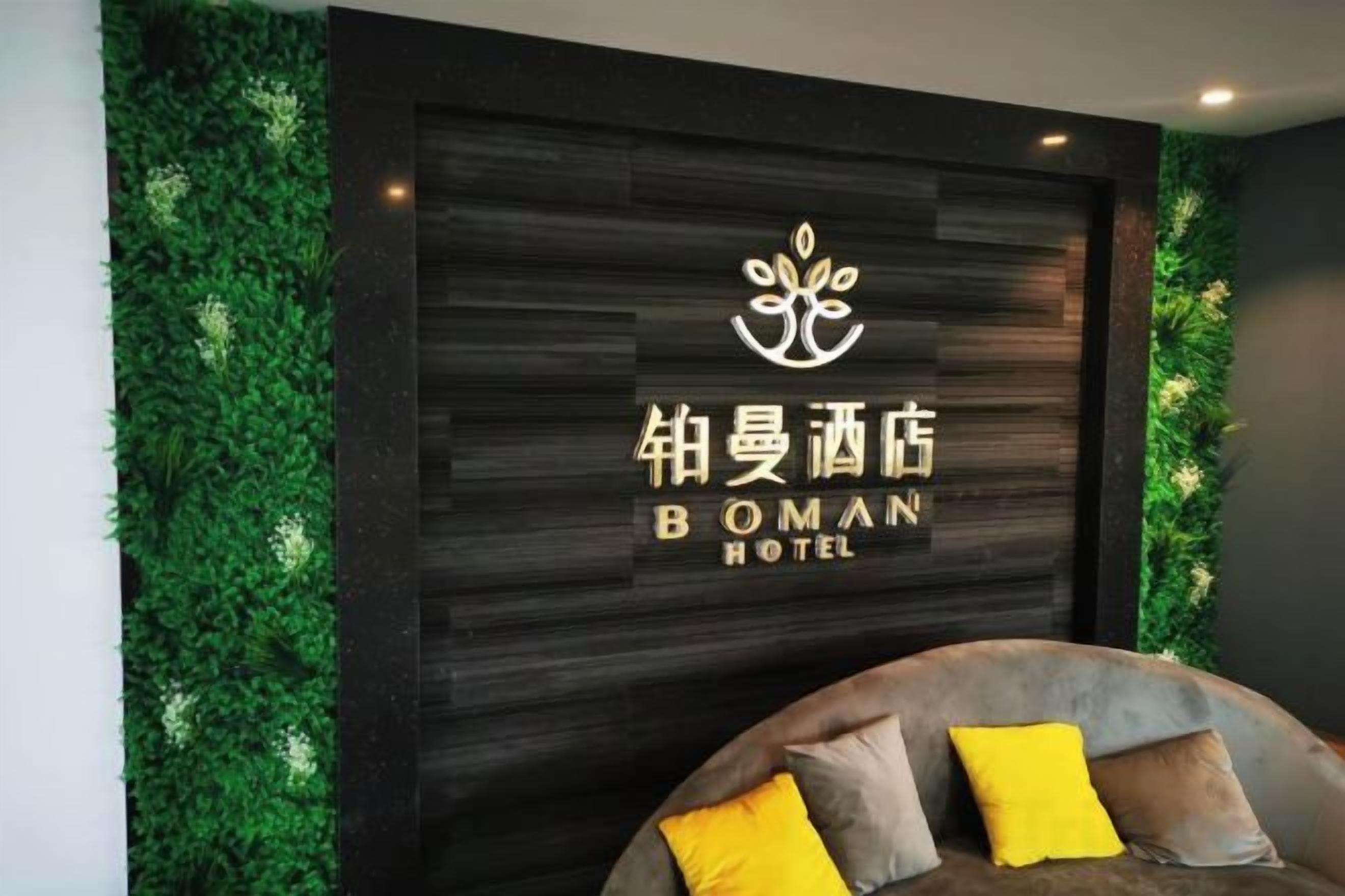 Zona de recepción de un hotel con un logotipo y el nombre 'BOMAN HOTEL' en una pared oscura.