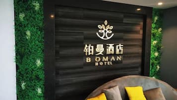 Zona de recepción de un hotel con un logotipo y el nombre 'BOMAN HOTEL' en una pared oscura.