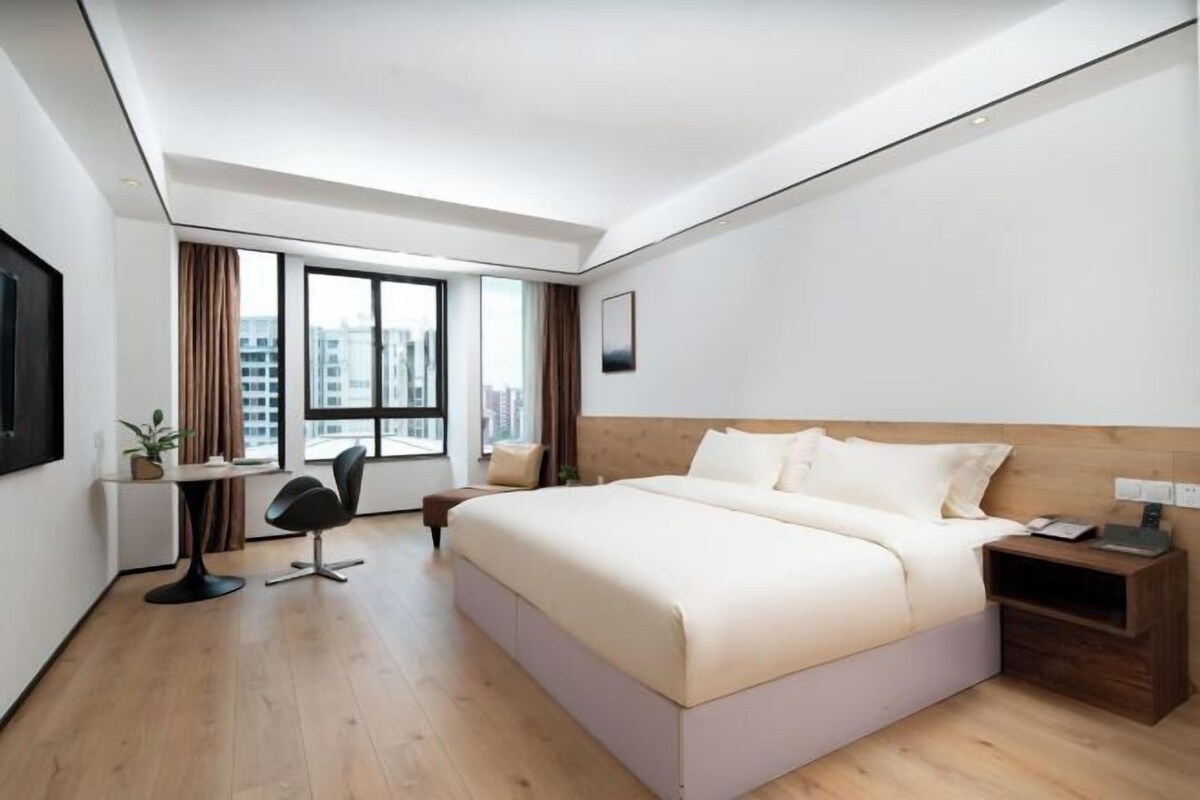 A modern hotel room with a large bed, a desk, and a chair.