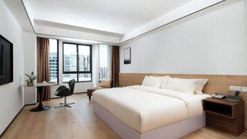 Una habitación de hotel moderna con una cama grande, un escritorio y una silla.