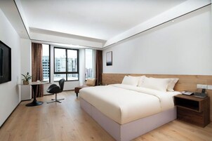 Una habitación de hotel moderna con una cama grande, un escritorio y una silla.