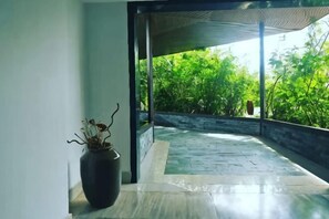 A room with a potted plant, a stone floor, and a view of greenery outside. - Bo Man Hotel (Pu'er)