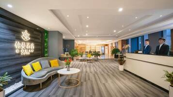 A hotel reception area with a sofa, a coffee table, and a reception desk.