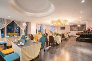 A restaurant with tables and chairs, a bar area, and a view of the outside. - Bo Man Hotel (Pu'er)