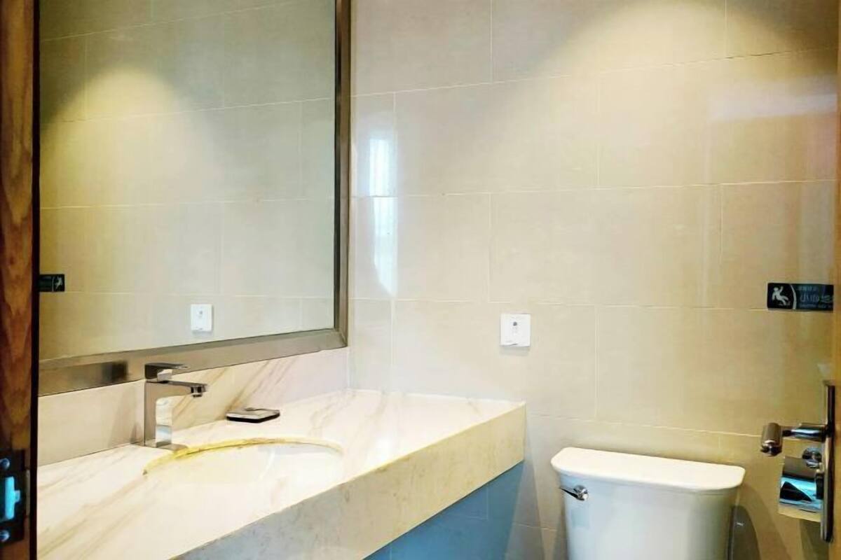 A bathroom with a marble vanity, a toilet, and a mirror.
