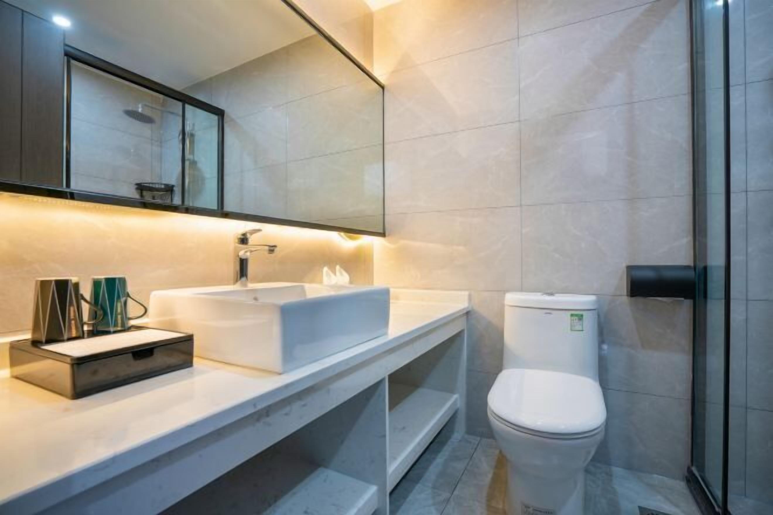 A modern bathroom with a white sink, mirror, and toilet.