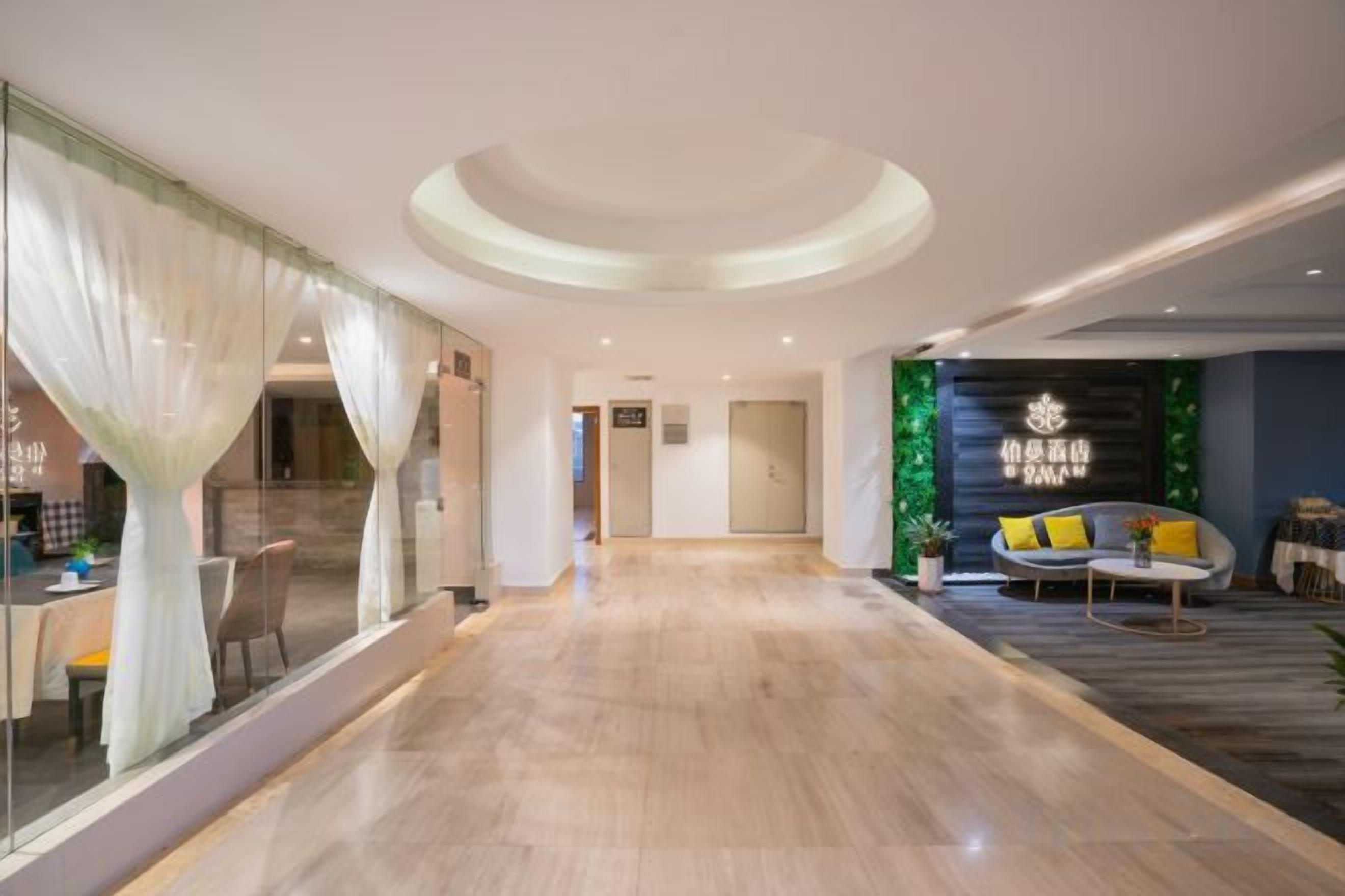 Eine Hotelhalle mit Holzboden, einer Couch mit Kissen, einer Glastrennwand und einer Wand mit einem Logo.