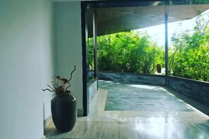A room with a large window, a potted plant, and a view of greenery outside. - Bo Man Hotel (Pu'er)