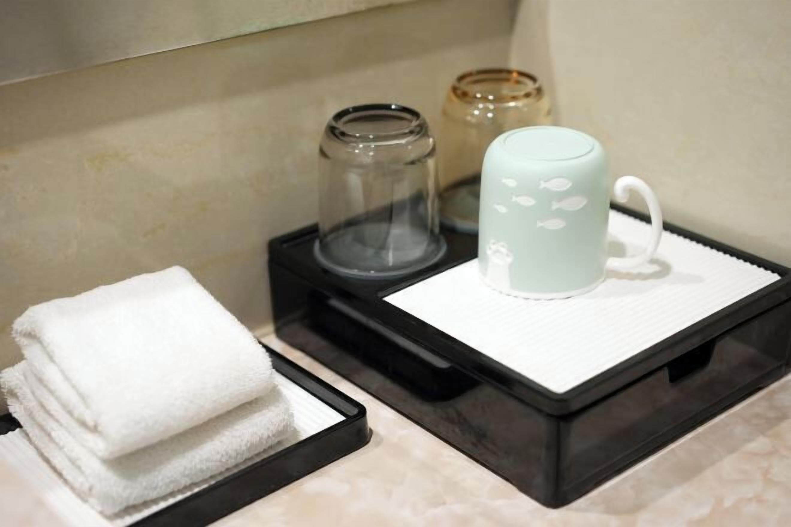 A bathroom with a towel rack, a glass jar, and a white mug on a tray.