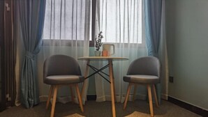 A room with two chairs and a small round table, a window with sheer curtains, and a plant on the windowsill. - YunZong hotel (Chongqing)