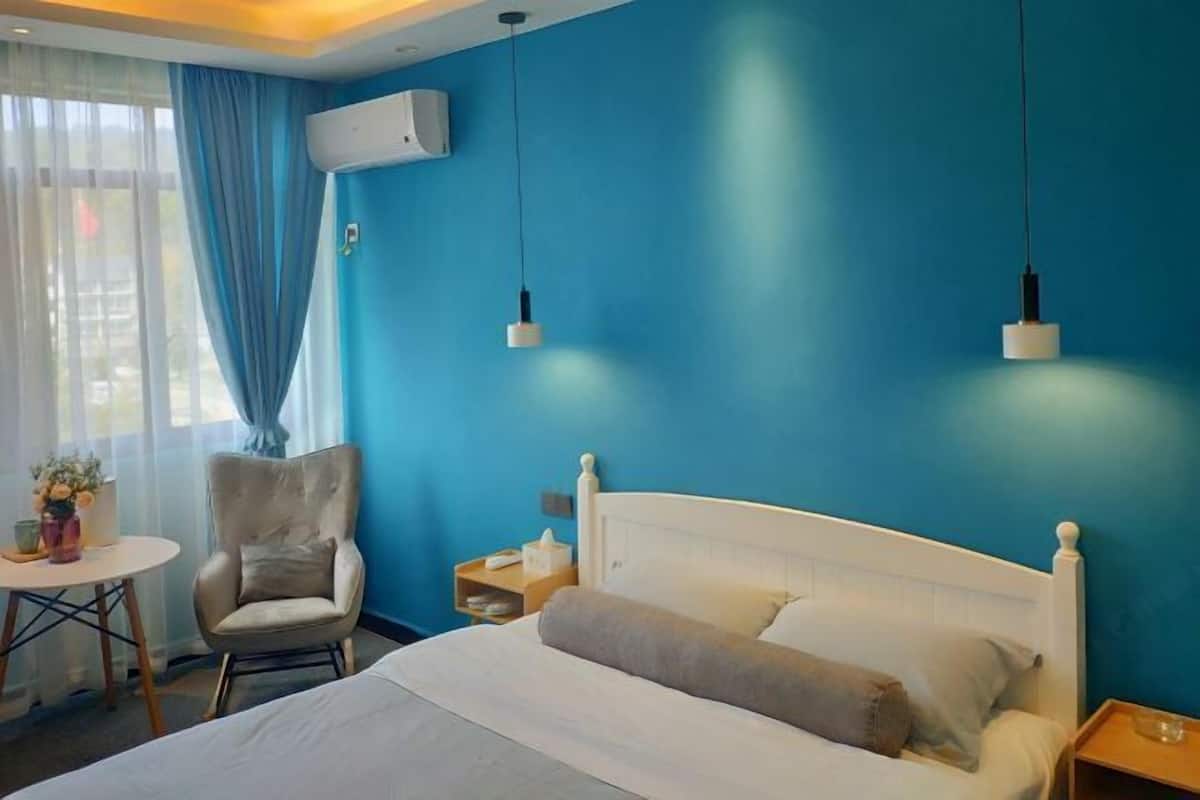 A hotel room with a bed, a chair, a small table, and a nightstand.