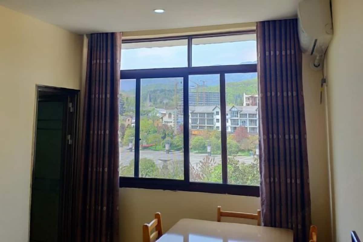 A room with a large window, a table, and two chairs.
