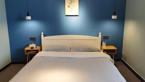 A hotel room with a large bed, two bedside tables, a nightstand, and a wall-mounted light fixture. - YunZong hotel (Chongqing)
