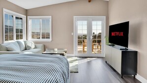 Une chambre moderne avec un grand lit, un téléviseur posé sur un meuble et un balcon avec vue.