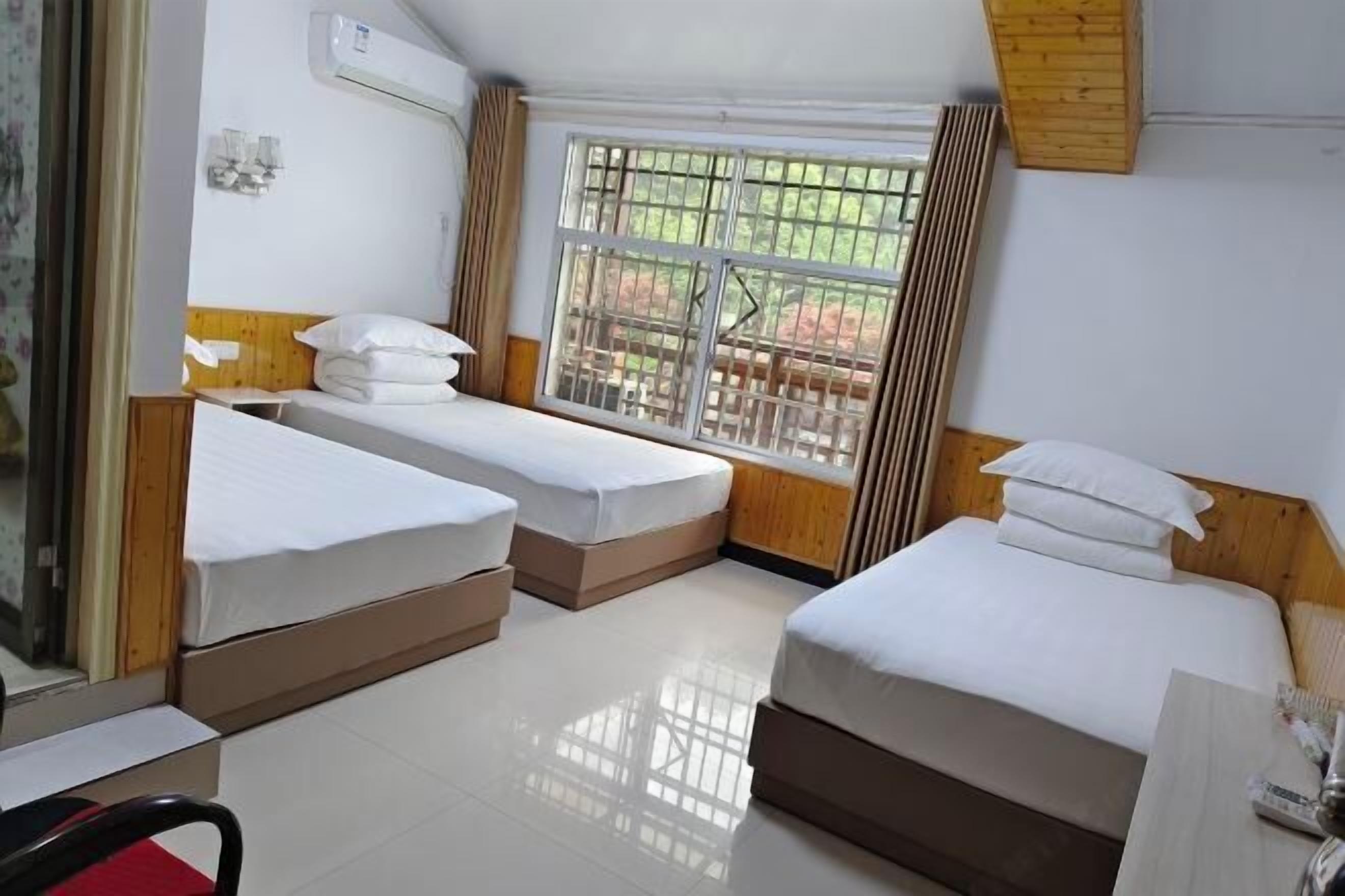 A hotel room with two beds, a window with bars, a wooden headboard, and a tiled floor.