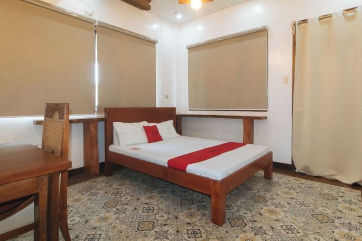 A bedroom with a wooden bed, a small table, and a patterned floor.