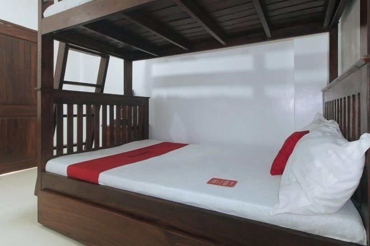 A bunk bed with a wooden frame, white mattress, and red accents.