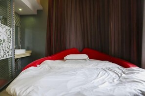 A modern hotel room with a red bed, white bedding, and a curtain backdrop. - Guests City Daren Theme Hotel (Laibin)