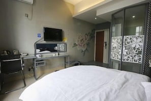 A hotel room with a bed, a desk with a flat-screen TV, a wall-mounted phone, and a decorative floral mural. - Guests City Daren Theme Hotel (Laibin)