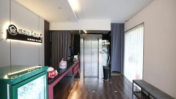 A hotel lobby with a reception desk, a refrigerator, a bench, and a door leading to another room. - Guests City Daren Theme Hotel (Laibin)