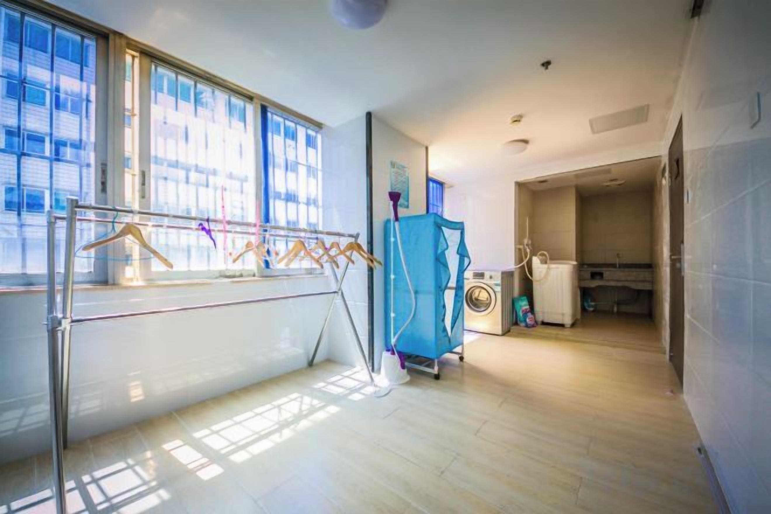 Habitació amb finestra gran, estendal, rentadora i zona de cuina.